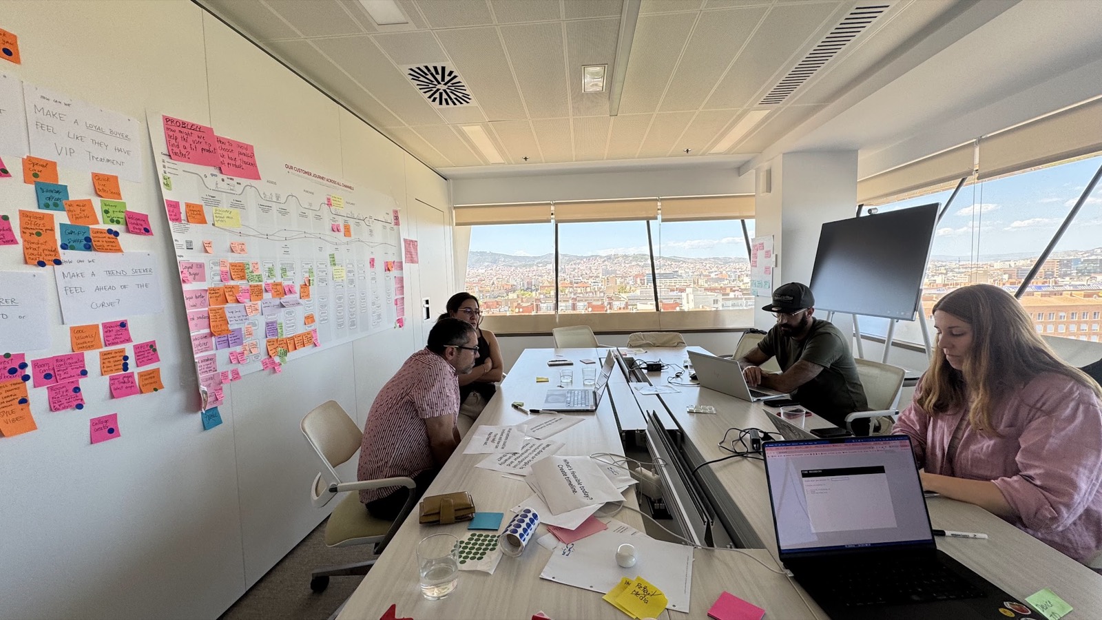 Equipo completo trabajando con laptops junto a la pared llena de post-its