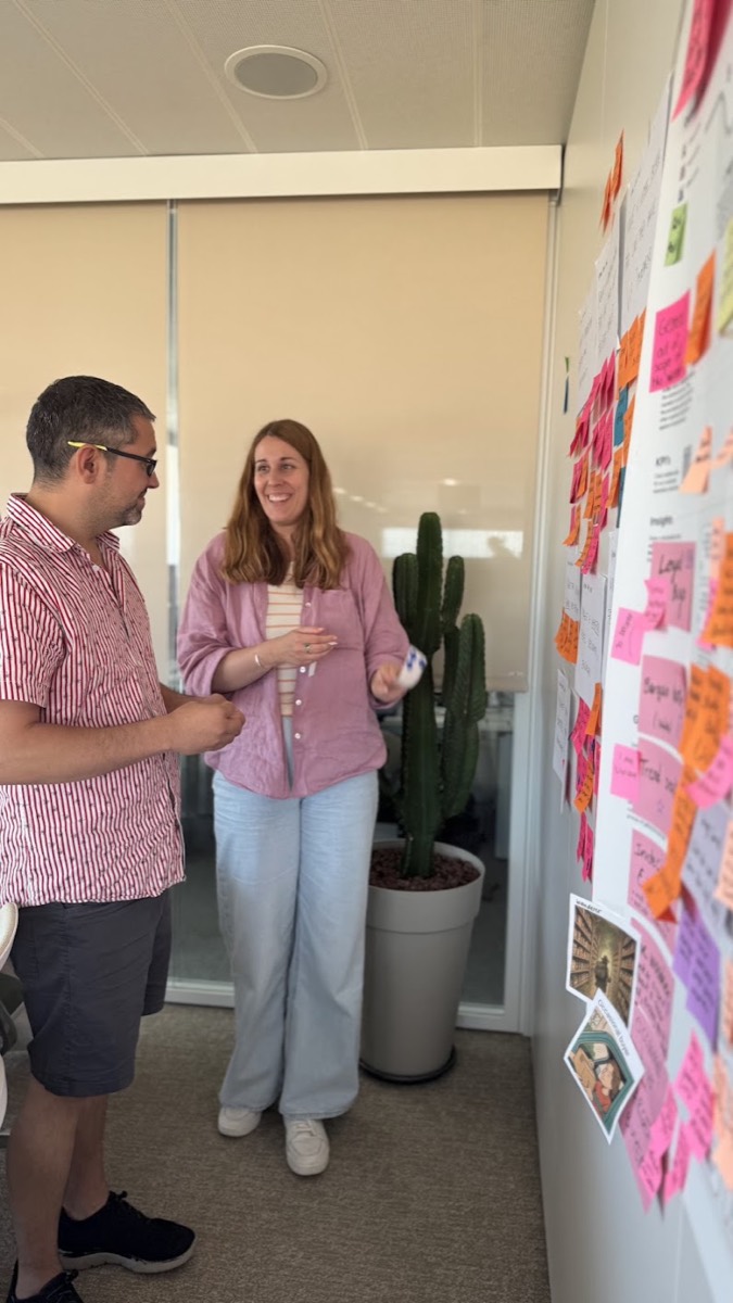 Dos personas del equipo conversando frente a la pared de personas y hallazgos
